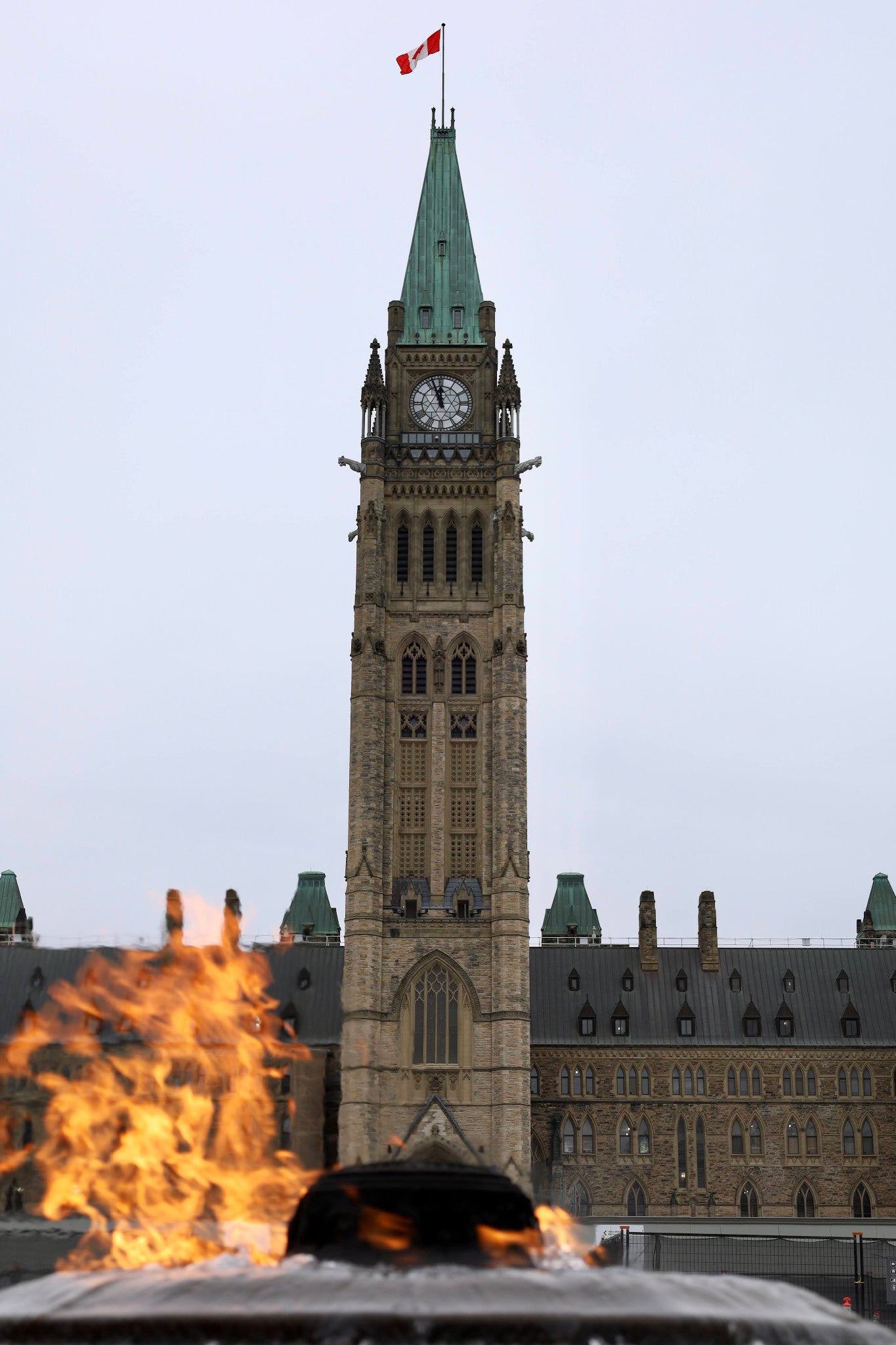 The Peace Tower and Canadian flag seen above the Centennial Flame on Parliament Hill