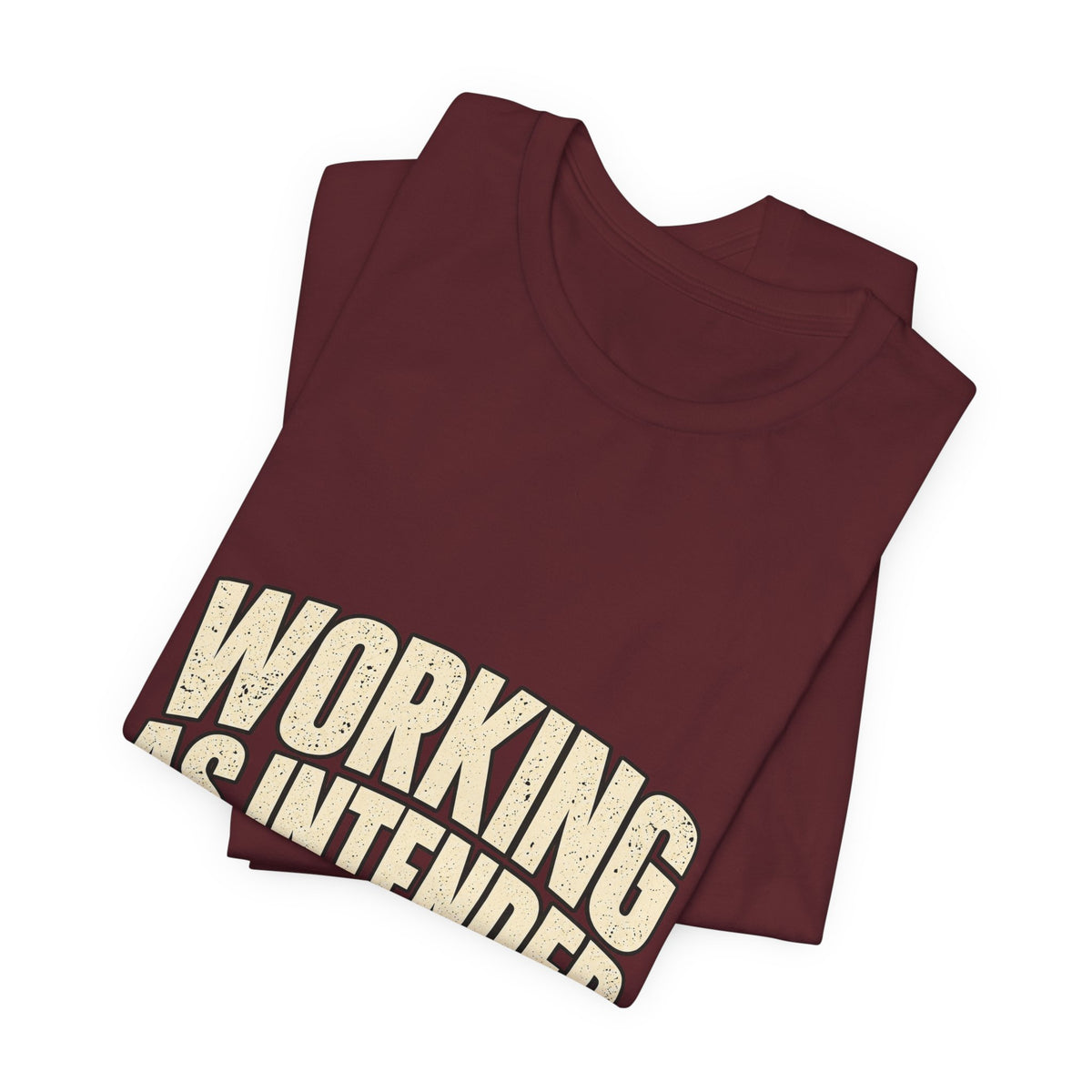 Folded maroon Working As Intended T-shirt showing a close view of the cream lettering.
